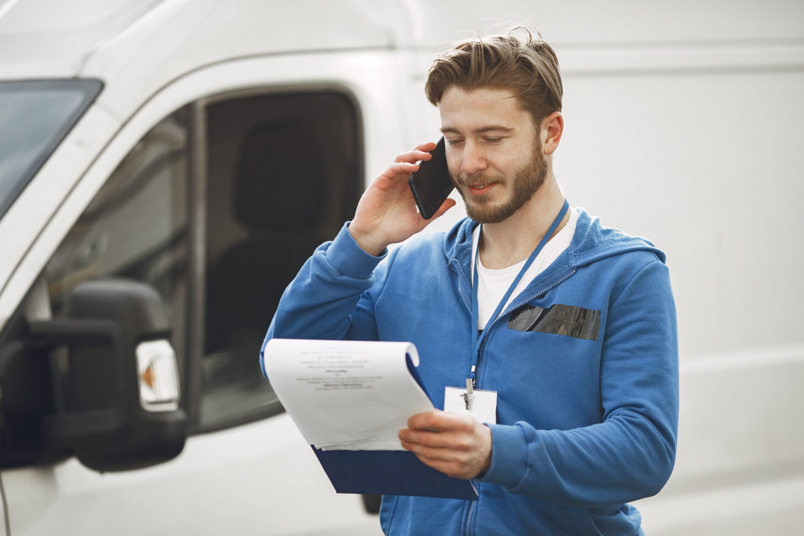 Local service professional using a phone beside a work van